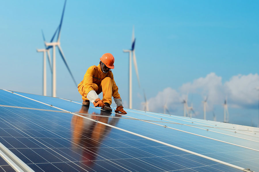 Discover-Texas-4 energy sector worked on solar panels with wind turbines in back