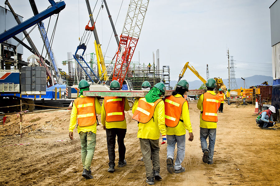 construction workers carrying equipment