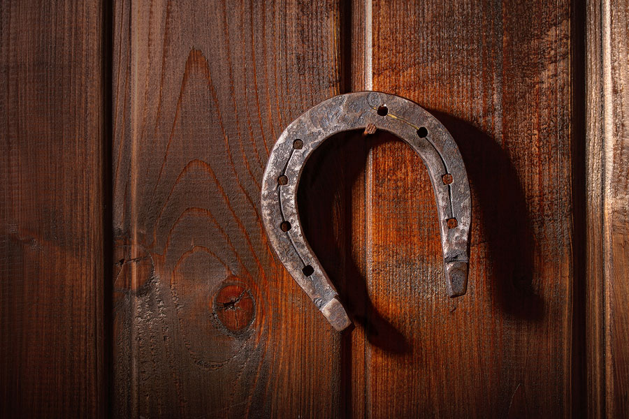 old horse horseshoe hanging horns down on a rusty nail on a dark wooden wall